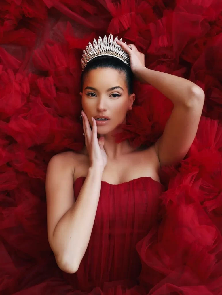 women laying down on a red dress with a crown