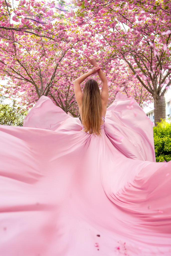 Cherry blossom photoshoot in Paris, flowing pink dress movement under blooming trees