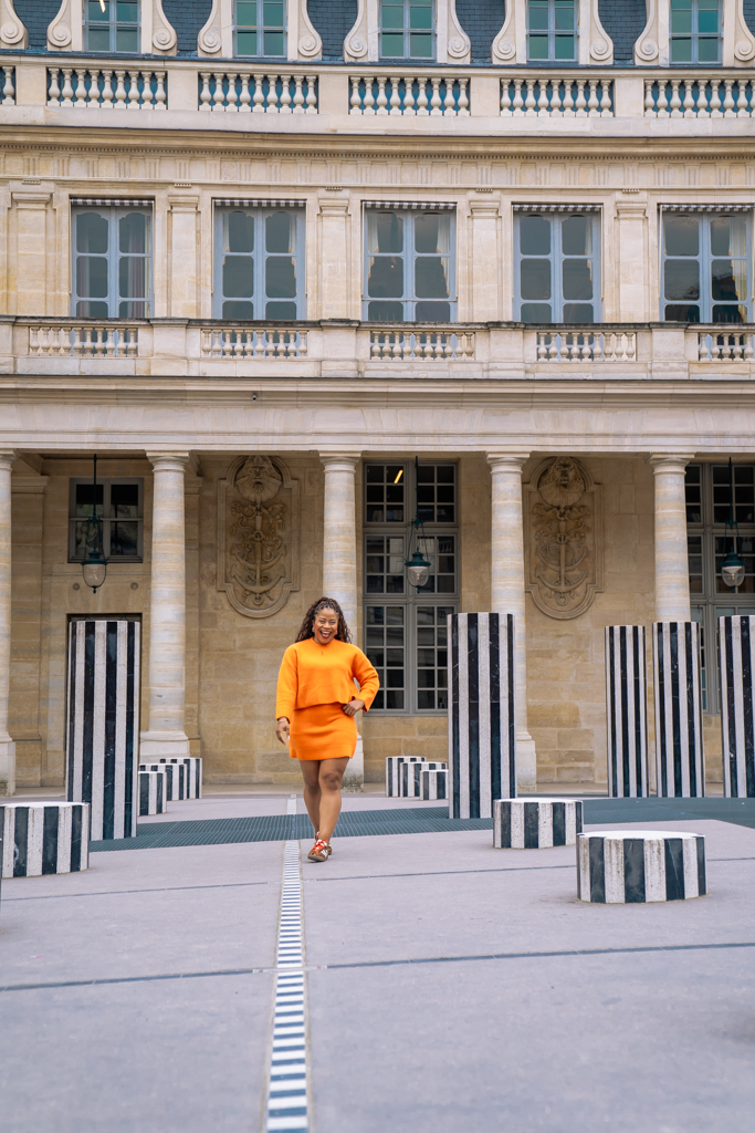 Palais Royal columns Paris photoshoot location with a woman walking between black and white pillars